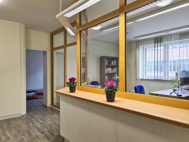 Empfangstresen mit Glasfront, dahinter das Büro