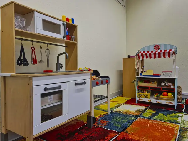 Spielecke mit Kinderküche, Kaufladen und buntem Teppich