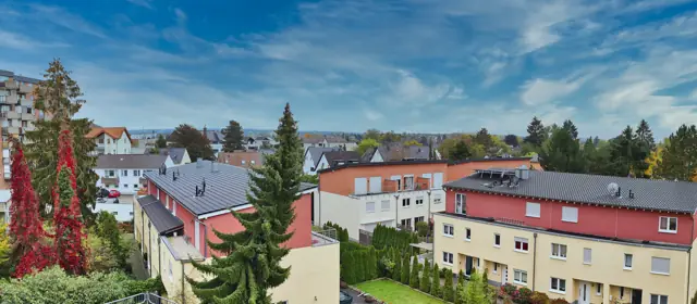 Panoramablick über Wohnhäuser und Bäume unter blauem Himmel