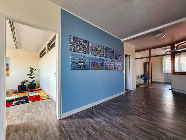 Diele mit blauer Wand und Bildergalerie, links der Blick ins Wartezimmer