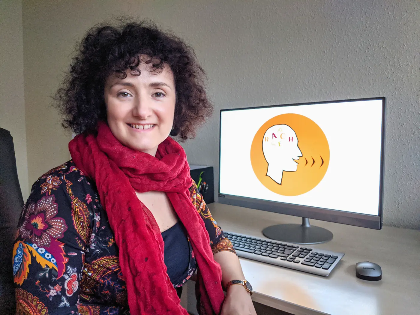Katerina Passameras an ihrem Schreibtisch, auf dem Bildschirm das Logo der Praxis