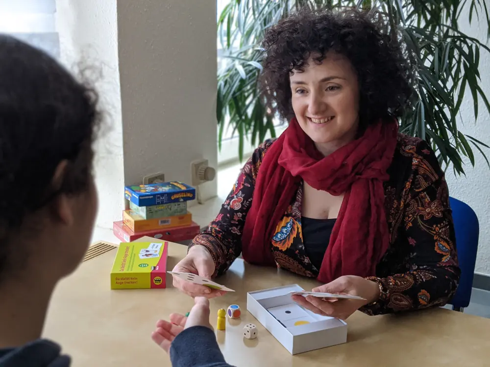 Therapiestunde: Katerina Passameras spielt mit einem Kind ein Kartenspiel am Tisch
